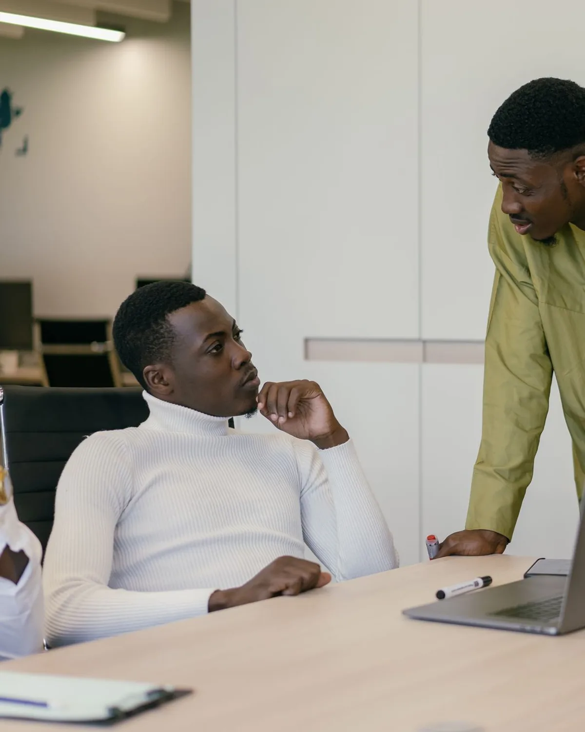 Colleagues discussing plans at a laptop in a modern office