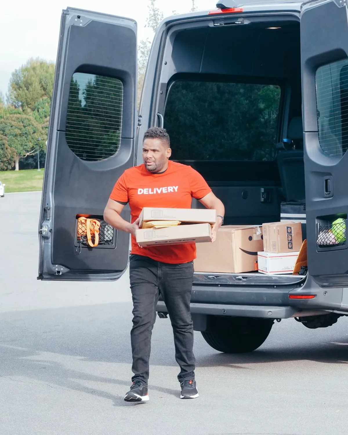 A courier carrying a parcel from his delivery van
