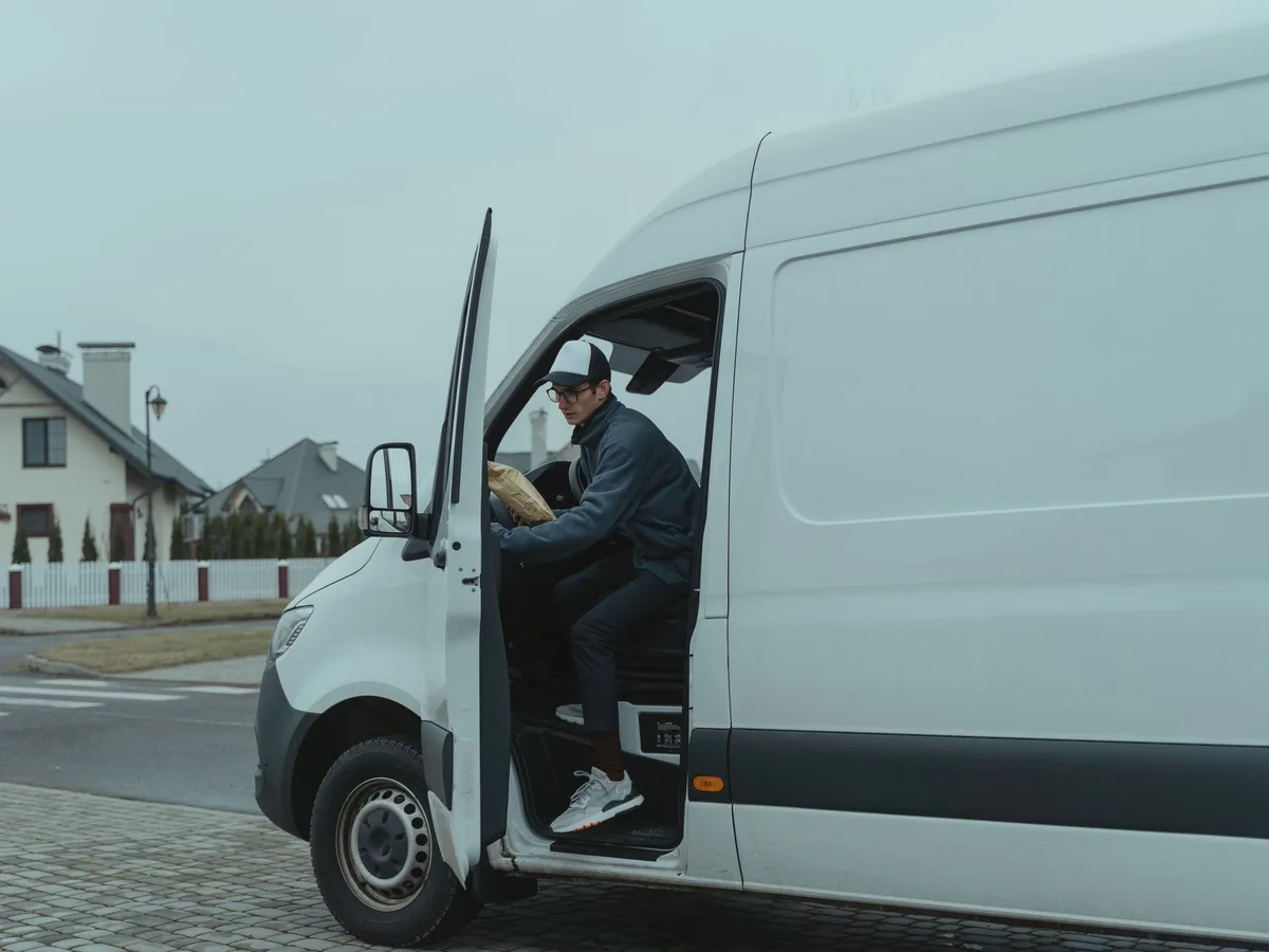 A driver stepping out of a delivery van